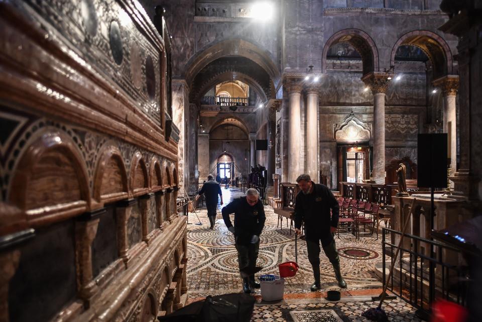 People mop the floor of the flooded St. Mark's Basilica after an exceptional overnight "Alta Acqua" high tide water level, on November 13, 2019 in Venice. - Powerful rainstorms hit Italy on November 12, with the worst affected areas in the south and Venice, where there was widespread flooding. Within a cyclone that threatens the country, exceptional high water were rising in Venice, with the sirocco winds blowing northwards from the Adriatic sea against the lagoons outlets and preventing the water from flowing back into the sea. At 22:40pm the tide reached 183 cm, the second measure in history after the 198 cm of the 1966 flood. (Photo by Marco Bertorello / AFP) (Photo by MARCO BERTORELLO/AFP via Getty Images)