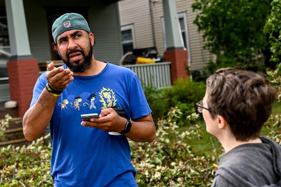 Simon Ponce, left, and Melissa Horste talk about the damage caused from the overnight storm on Thursday, July 13, 2023, on Lansing's east side.