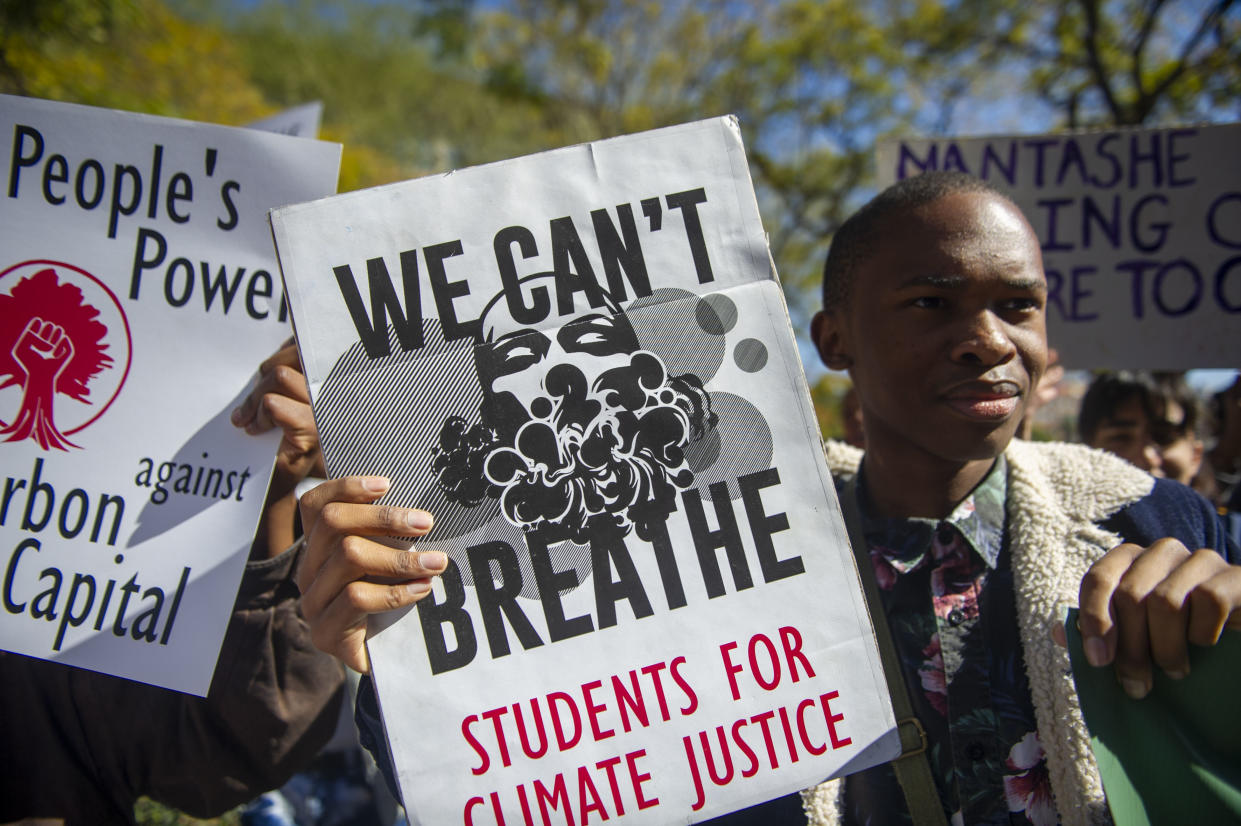 Members of the Climate Justice Coalition in Pretoria, South Africa, holding signs that read We Can't Breathe and People's Power Against Carbon Capital.