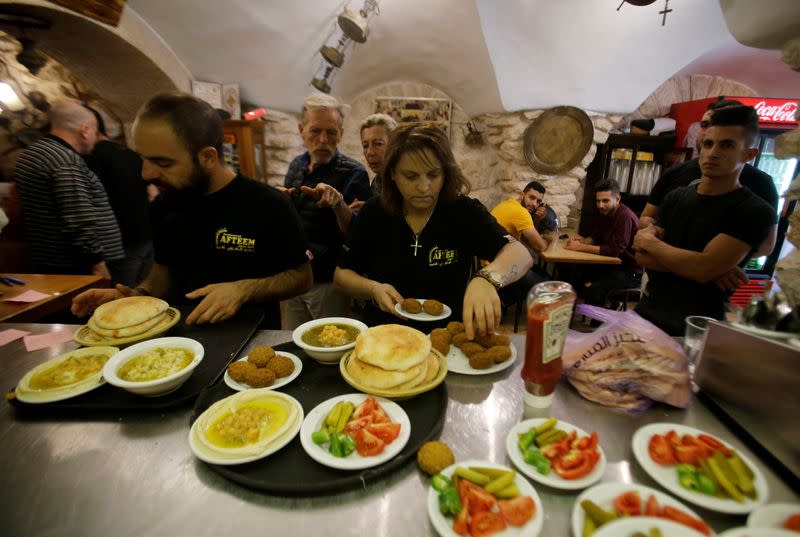 Palestinian waiters prepare Falafel and Hummus plates for customers of Afteem restaurant, owned by Palestinian man George Salameh, in Bethlehem