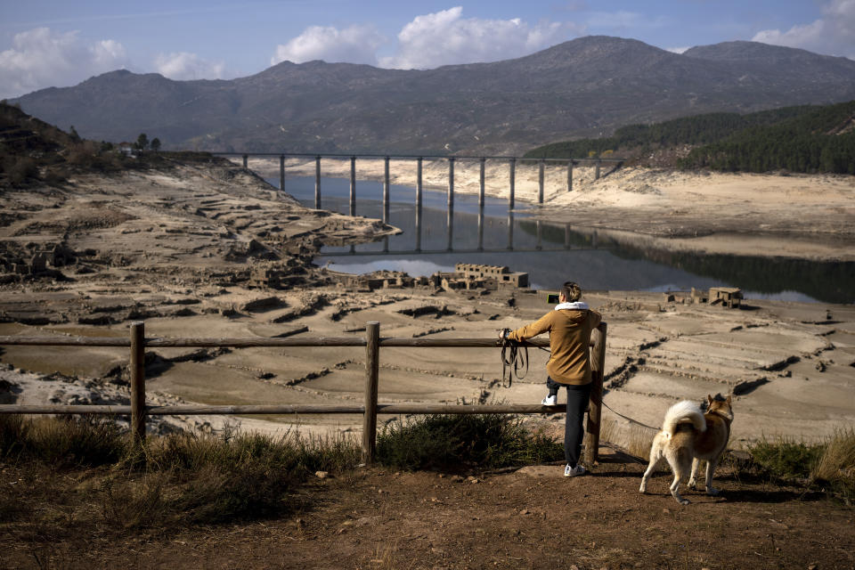 A man photographs the old village of Aceredo, submerged three decades ago when a hydropower dam flooded the valley and emerged now due to drought at the Lindoso reservoir, in northwestern Spain, Saturday, Feb. 12, 2022. With rainfall levels this winter at one-third of the average in recent years, large swaths of Spain are experiencing extreme or prolonged drought. The situation is similar in neighboring Portugal, where 45% of the country was enduring "severe" or "extreme" drought conditions by the end of January, according to authorities. (AP Photo/Emilio Morenatti)