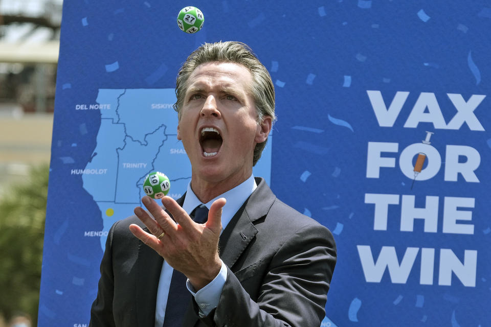 California Gov. Gavin Newsom juggles balls with winning numbers after the Vax for the Win lottery contest during a news conference at Universal Studios in Universal City, Calif., Tuesday, June 15, 2021. On Tuesday, California lifted most of its COVID-19 restrictions and ushered in what has been billed as the state’s “Grand Reopening.” (AP Photo/Ringo H.W. Chiu)