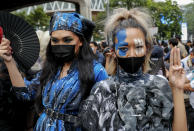 Members of LGBT community, supporters of pro-democracy in costumes flash three-fingered salute during a protest rally at Ratchaprasong business district in Bangkok, Thailand, Sunday, Oct. 25, 2020. Pro-democracy protesters in Thailand gathered again Sunday in Bangkok, seeking to keep up pressure on the government a day ahead of a special session of Parliament called to try to ease political tensions. (AP Photo/Gemunu Amarasinghe)