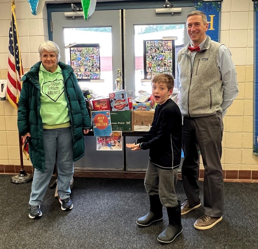 Benjamin Deely, a fourth-grader at Barrington Elementary School, center, stands next to boxes of goods collected during a donation drive at the school. He is joined by, left, Susan Danforth, a volunteer at the Willand Warming Center of Strafford County in Somersworth, and Barrington Elementary School Principal Rich Boardman.