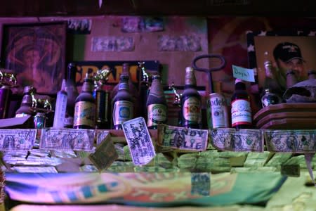 Dollar bills signed by past customers are seen at The Field Office bar in Midland