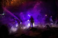 Firefighters try to put out fires on the street during clashes between protestors and police in Barcelona, Spain, Wednesday, Oct. 16, 2019. Spain's government said Wednesday it would do whatever it takes to stamp out violence in Catalonia, where clashes between regional independence supporters and police have injured more than 200 people in two days. (AP Photo/Bernat Armangue)