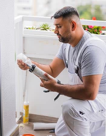 A man in white overalls looks at a product label. 