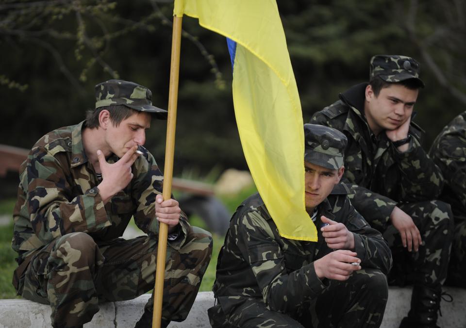 Ukrainian servicemen hold a Ukrainian flag before leaving the Belbek airbase near Sevastopol, Crimea, Friday, March 28, 2014. Ukraine started withdrawing its troops and weapons from Crimea, now controlled by Russia. Russia's president says Ukraine could regain some arms and equipment of military units in Crimea that did not switch their loyalty to Russia. (AP Photo/Andrew Lubimov)