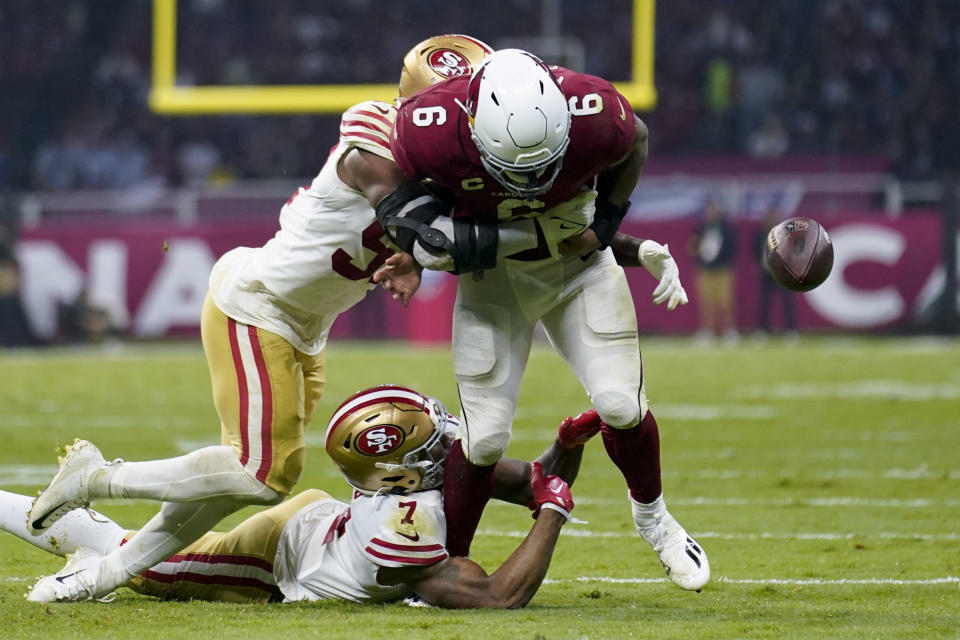 Arizona Cardinals running back James Conner, right, loses control of the ball as he is hit by San Francisco 49ers quarterback Trey Lance, above, and cornerback Charvarius Ward, below, during the first half of an NFL football game Monday, Nov. 21, 2022, in Mexico City. (AP Photo/Marcio Jose Sanchez)