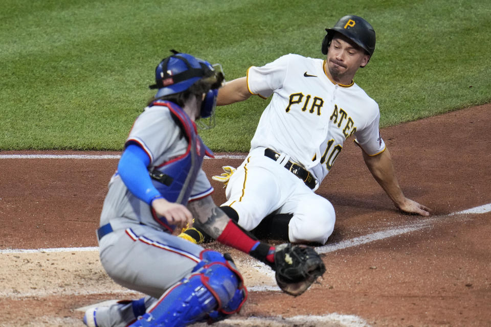 Pittsburgh Pirates' Bryan Reynolds, right, gets under the tag attempt by Texas Rangers catcher Jonah Heim to score on a single by Carlos Santana off Rangers relief pitcher Josh Sporz during the seventh inning of a baseball game in Pittsburgh, Monday, May 22, 2023. (AP Photo/Gene J. Puskar)