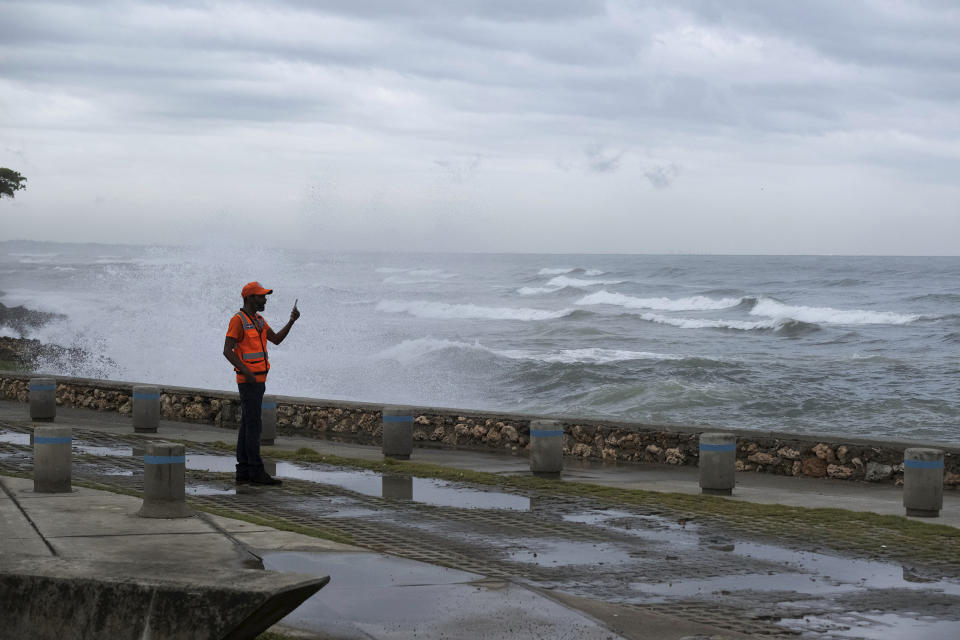 A man takes photos with his phone as the waves caused by Tropical Storm Franklin break on the sea wall in Santo Domingo, Dominican Republic, Tuesday, Aug. 22, 2023. (AP Photo/Ricardo Hernandez)