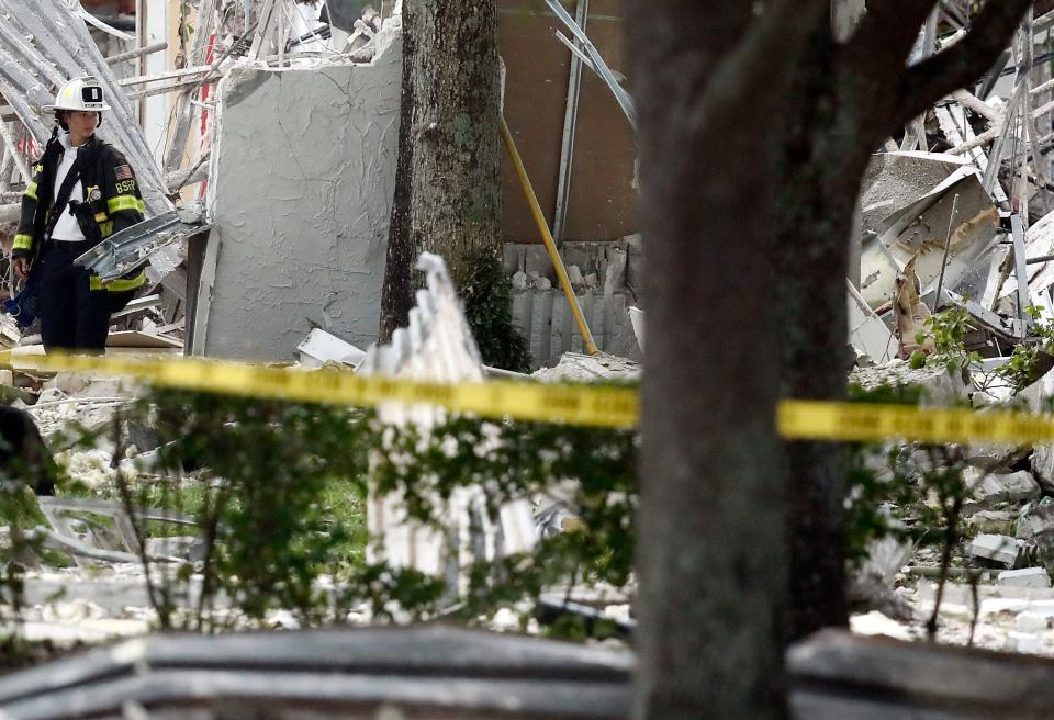 A firefighter looks at the remains of a building after an explosion on Saturday, July 6, 2019, in Plantation, Fla.