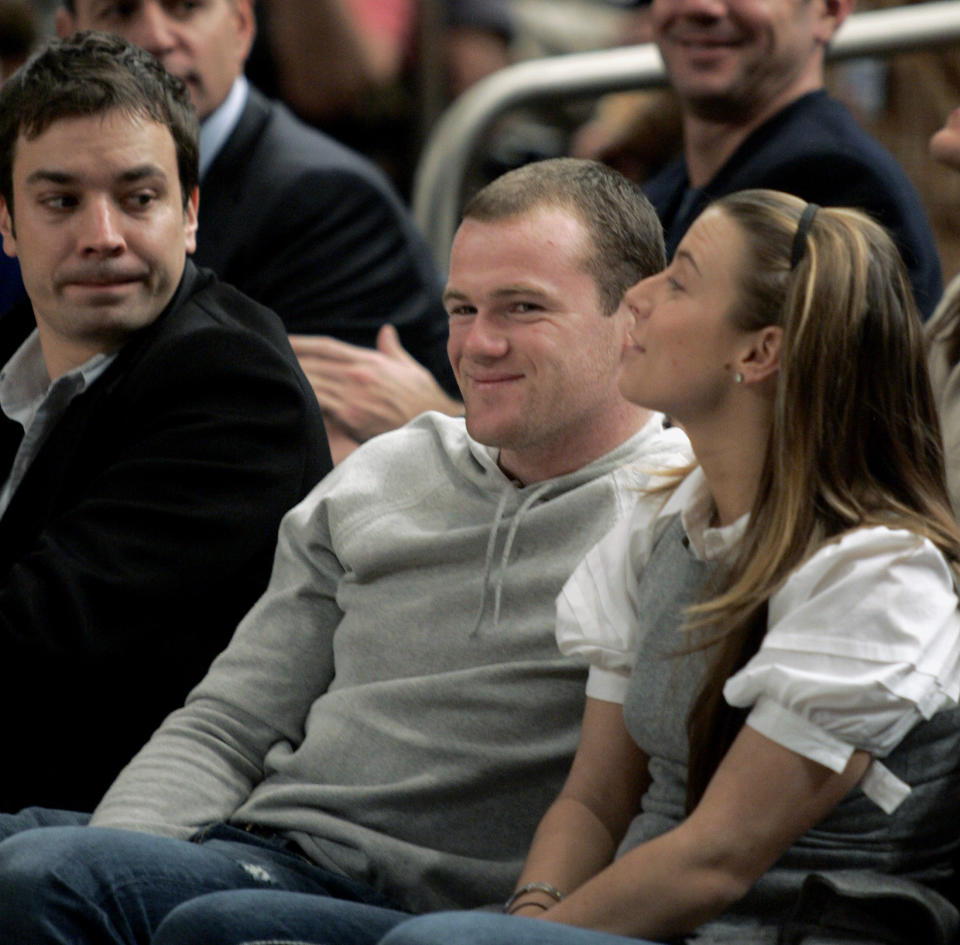 Actor Jimmy Fallon (L) watches as Manchester United player Wayne Rooney (C) smiles as he is introduced to the crowd at new York's Madison Square Garden during the Boston Celtics game with the New York Knicks, December 11, 2006. His girlfriend Coleen McLoughlin (R) sits with him. REUTERS/Ray Stubblebine (UNITED STATES)