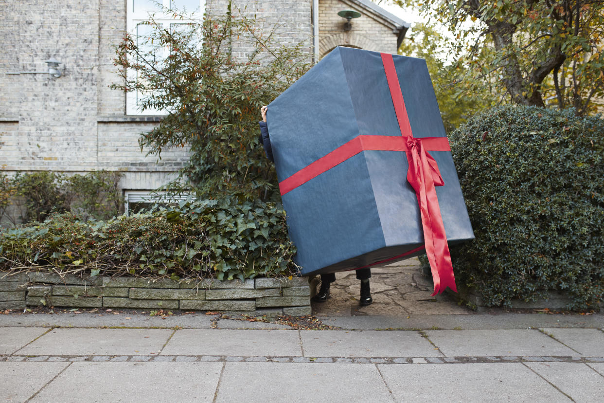 Low section of woman carrying large wrapped gift box on footpath