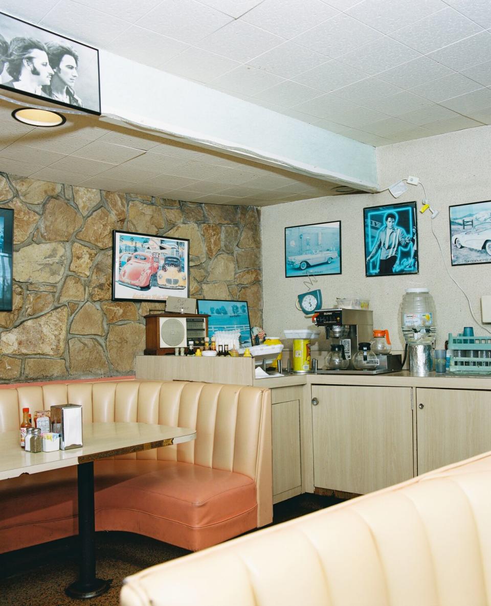 A photo of tan booths in a diner with a photo of Elvis Presley on the wall.