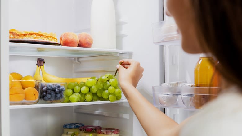 Person grabbing fruit from fridge