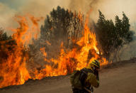 <p>A firefighter covers his face while battling a wildfire near Morgan Hill, Calif., Tuesday, Sept. 27, 2016. The grass fire along a Northern California highway spread to parched trees, and flying embers landed on nearby homes, setting at least eight homes on fire, authorities said. (AP Photo/Noah Berger) </p>