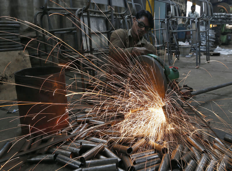 A worker cuts a metal pipe inside a steel furniture production factory in Ahmedabad February 2, 2015. REUTERS/Amit Dave