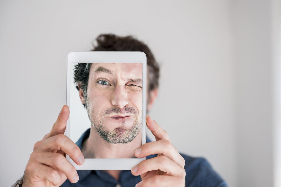 man making faces while taking selfie with iPad