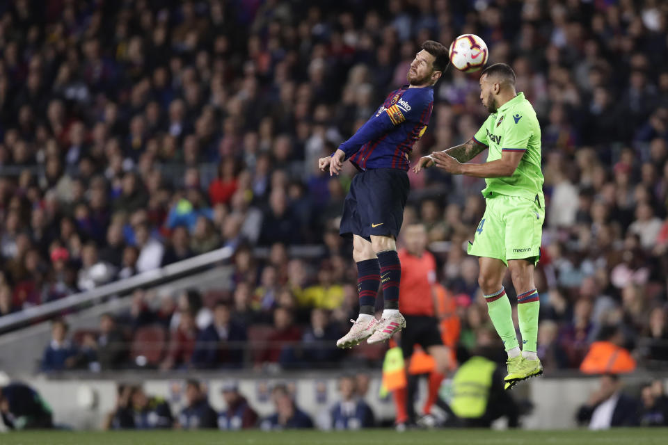Barcelona forward Lionel Messi, left, jumps for the ball with Levante's Ruben Vezo during a Spanish La Liga soccer match between FC Barcelona and Levante at the Camp Nou stadium in Barcelona, Spain, Saturday, April 27, 2019. (AP Photo/Manu Fernandez)