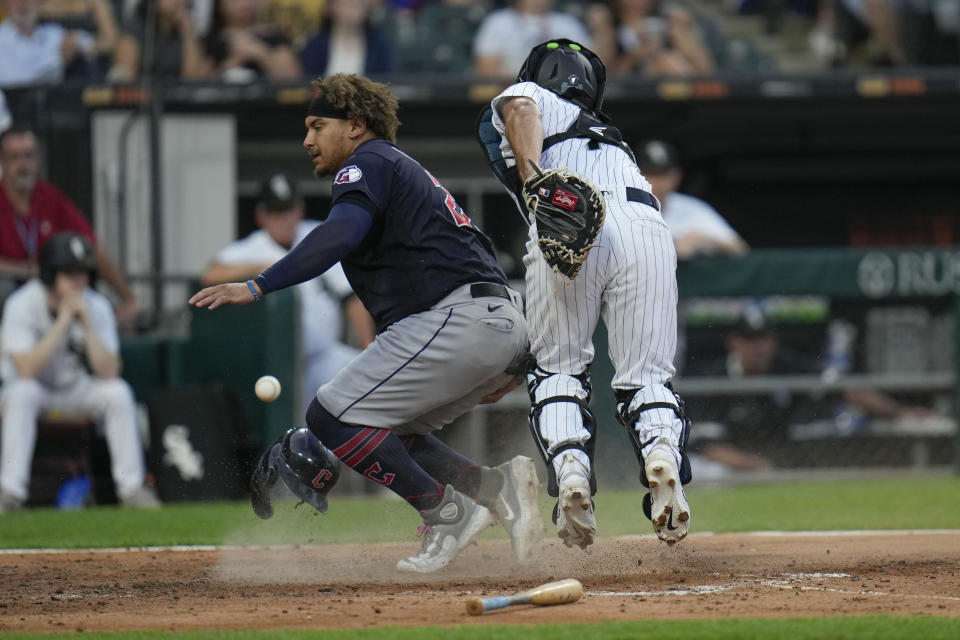 Cleveland Guardians' Josh Naylor, left, loses his helmet and Chicago White Sox catcher Seby Zavala loses the ball as Naylor scores during the third inning of a baseball game Thursday, July 27, 2023, in Chicago. (AP Photo/Erin Hooley)