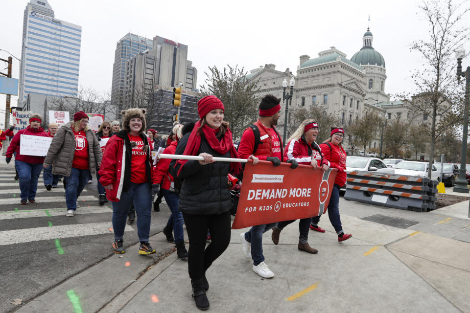 Thousands of Indiana teachers wearing red march around the Statehouse in Indianapolis, Tuesday, Nov. 19, 2019 following a rally calling for further increasing teacher pay in the biggest such protest in the state amid a wave of educator activism across the country. Teacher unions says about half of Indiana's nearly 300 school districts are closed while their teachers attend Tuesday's rally while legislators gather for 2020 session organization meetings.(AP Photo/Michael Conroy)