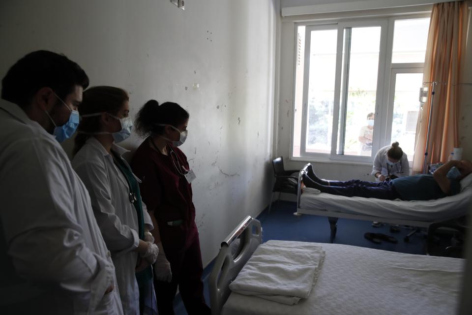 In this photo taken on Wednesday, May 6, 2020, Katerina Bakiri examines a patient as medical students Nikolaos Syrigos, left, Eleni Fyta, center, and Adamantia Papamichail look on at the Pathological Clinic of Sotiria Hospital in Athens. Greece's main hospital for the treatment of COVID-19 is also the focus of a hands-on training program for dozens of medical students who volunteered to relieve hard-pressed doctors from their simpler duties while gaining a close peek at the front lines of a struggle unmatched in modern medical history. (AP Photo/Thanassis Stavrakis)