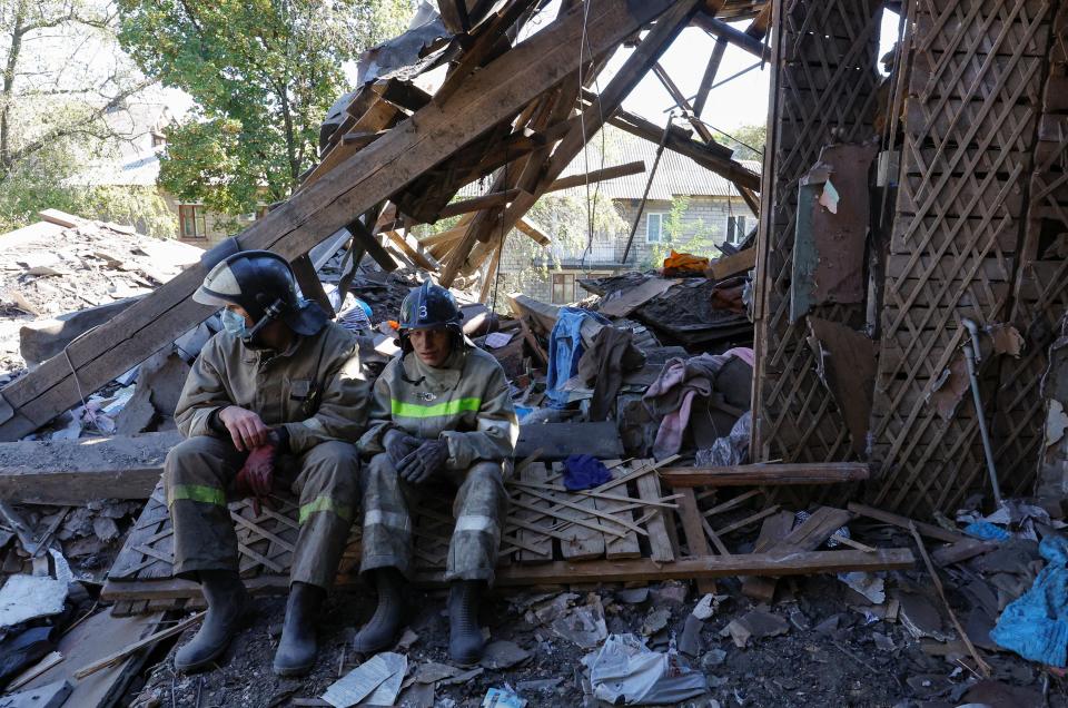 Rescuers sit amid debris of a house heavily damaged by recent shelling (REUTERS)