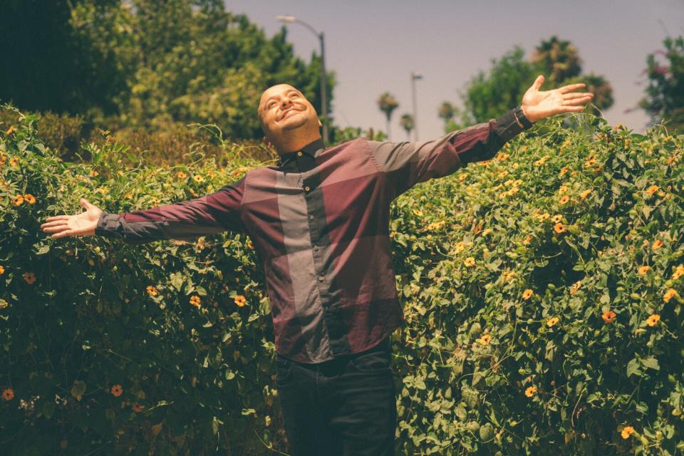 A man spreads his arms wide while looking up at the sky