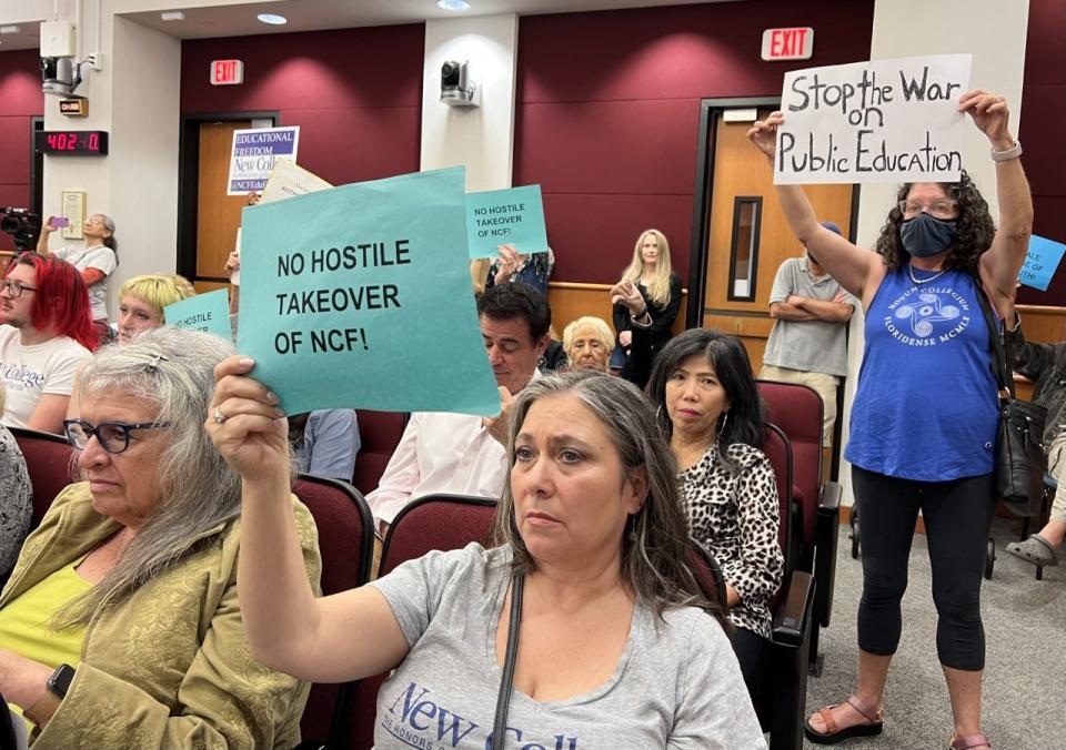 Tamara Solum of Sarasota, Fla., holds up a sign reading "NO HOSTILE TAKEOVER OF NCF!" during a meeting of the Sarasota County Legislative Delegation on Jan. 12, 2023. Solum's daughter attends New College of Florida.