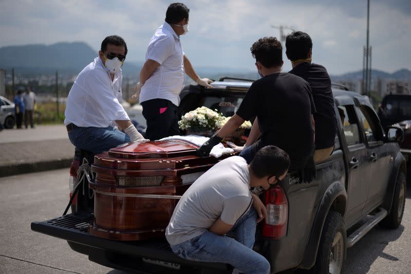 People wait next to a coffin in a pick-up truck lined up outside of a cemetery as Ecuador's government announced on Thursday it was building a "special camp" in Guayaquil for coronavirus disease (COVID-19) victims, in Guayaquil