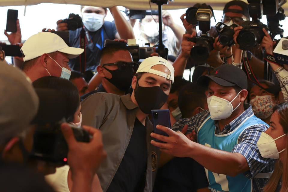 President Nayib Bukele poses for a selfie with a poll worker, as he votes in local and legislative elections at a polling station in San Salvador, El Salvador, Sunday, Feb. 28, 2021. The president's New Ideas party is hoping to loosen the decades-long hold on congress by the country's more established political parties. (AP Photo/Salvador Melendez)