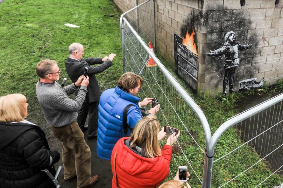PORT TALBOT, WALES - DECEMBER 20: People gather around fences that have been erected to protect the latest piece of artwork by the underground guerrilla artist Banksy on December 20, 2018 in Port Talbot, Wales. The British graffiti artist who keeps his identity a secret, confirmed yesterday that the artwork was his using his verified Instagram account to announce