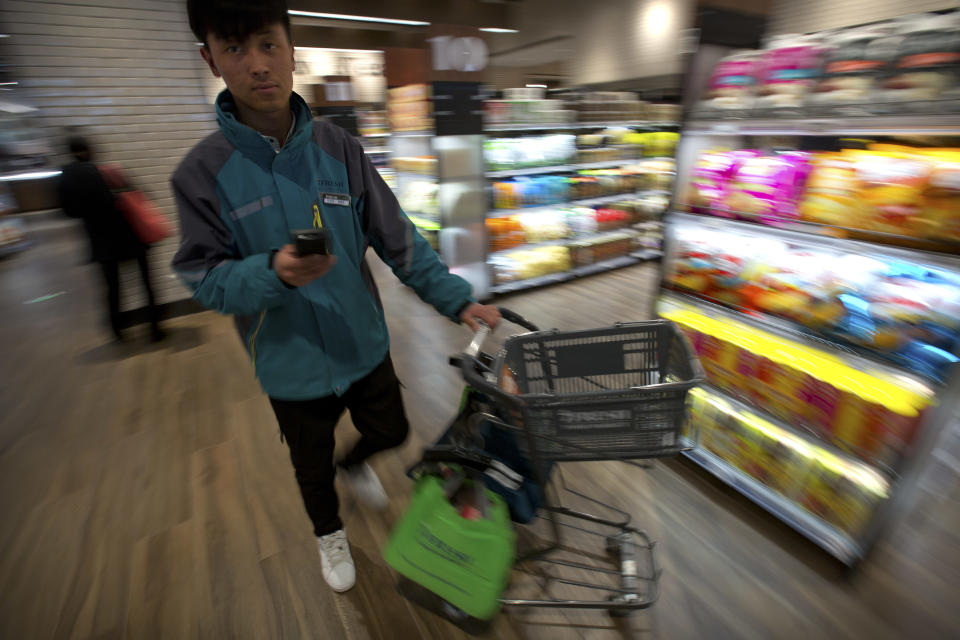 In this March 30, 2018, photo, a courier pushes a shopping cart as he fills an online order at a 7FRESH grocery store operated by Chinese e-commerce retailer JD.com in Beijing, China. The Chinese e-commerce billionaire who faces a possible rape accusation in Minneapolis built his business by promising honesty in a market plagued by fraud and fakes. (AP Photo/Mark Schiefelbein)