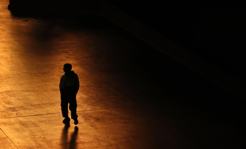 In this April 18, 2020, photo, person walks along the Las Vegas Strip devoid of the usual crowds as casinos and other business are shuttered due to the coronavirus outbreak in Las Vegas. (AP Photo/John Locher)