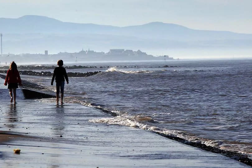 A person walking along the seafront during a hot day