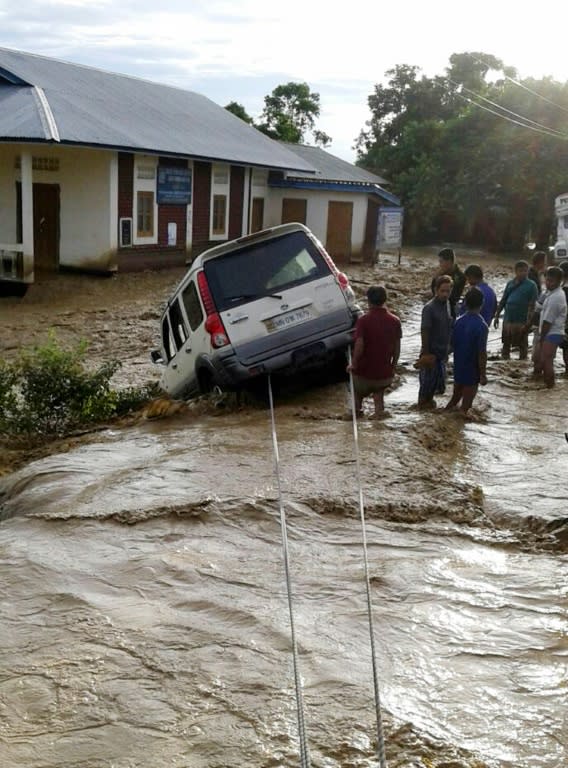 People try to retrieve a car which is stuck in the flood water at the flood affected Thoubal district in Manipur state on August 2, 2015