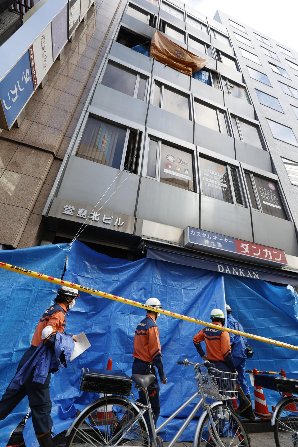 Investigators enter into a building where a fire broke out in Osaka, western Japan Saturday, Dec. 18, 2021. A fire that spread from a fourth-floor mental clinic in the eight-story building in downtown Osaka on Friday left more than 20 dead in what police were investigating as a possible case of arson and murder. (Kyodo News via AP)