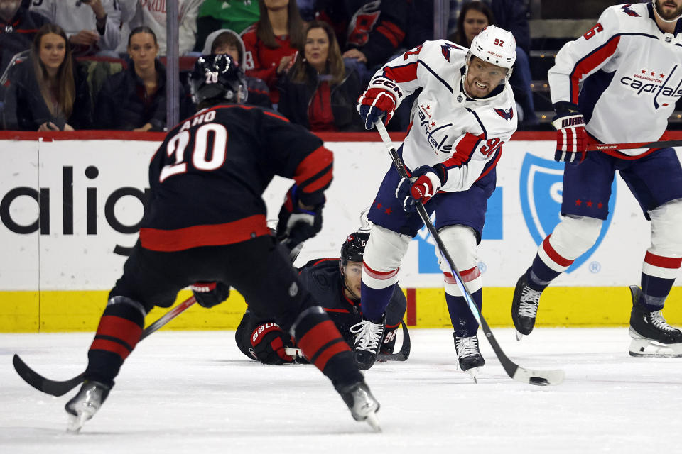 Washington Capitals' Evgeny Kuznetsov (92) passes the puck past Carolina Hurricanes' Sebastian Aho (20) during the first period of an NHL hockey game in Raleigh, N.C., Sunday, Dec. 17, 2023. (AP Photo/Karl B DeBlaker)