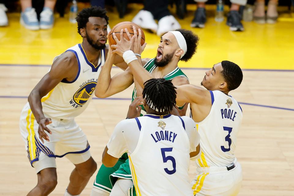 Boston Celtics guard Derrick White shoots against Golden State Warriors forward Andrew Wiggins, left, center Kevon Looney and guard Jordan Poole  during the second half of Game 1 of the NBA Finals in San Francisco.