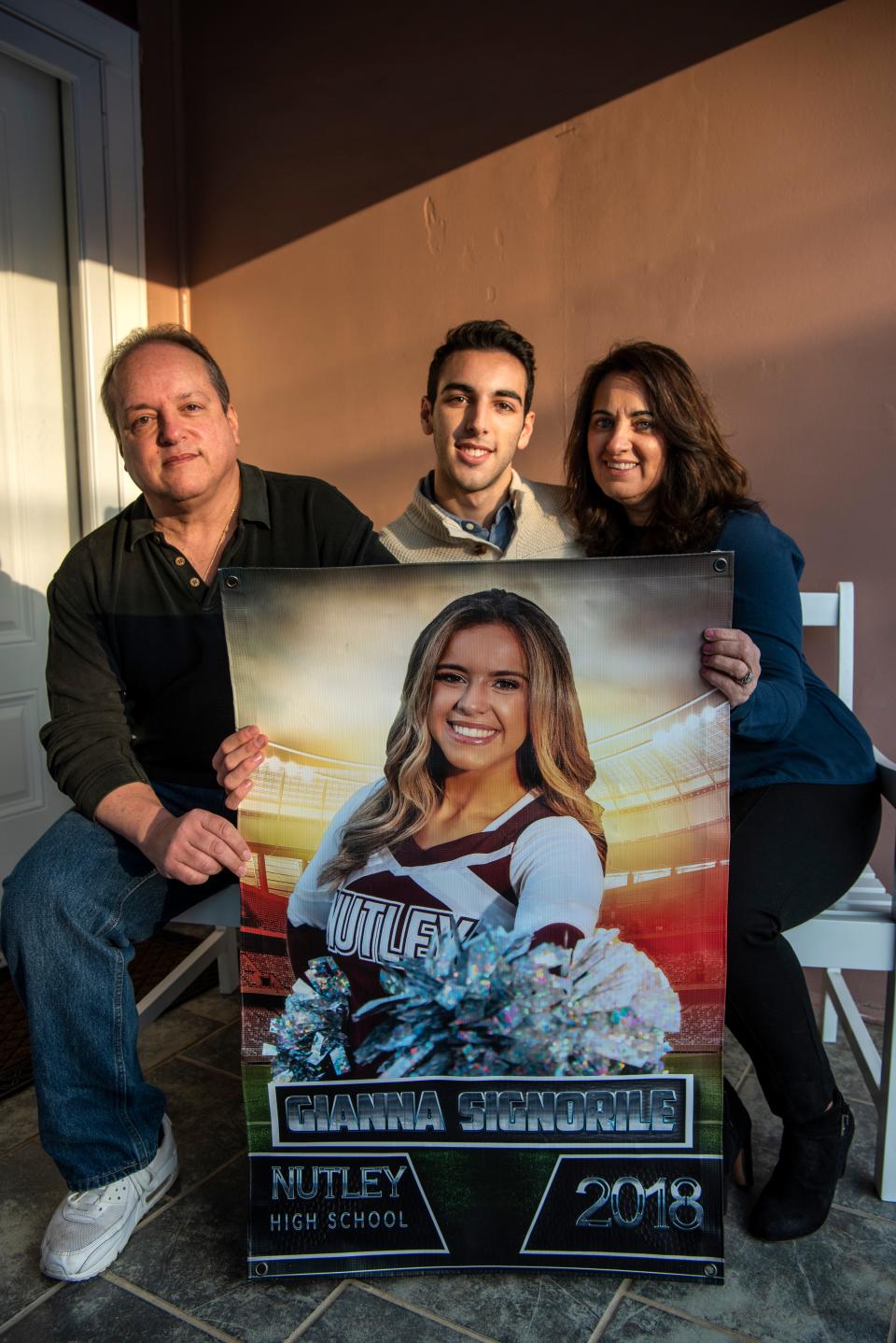 (Left) John Signorile, his son John Jr., and his wife Dawn hold a picture of Gianna Signorile on Friday, January 7, 2022. John and Dawn's daughter Gianna died of fibrolamellar carcinoma on December 20, 2021.