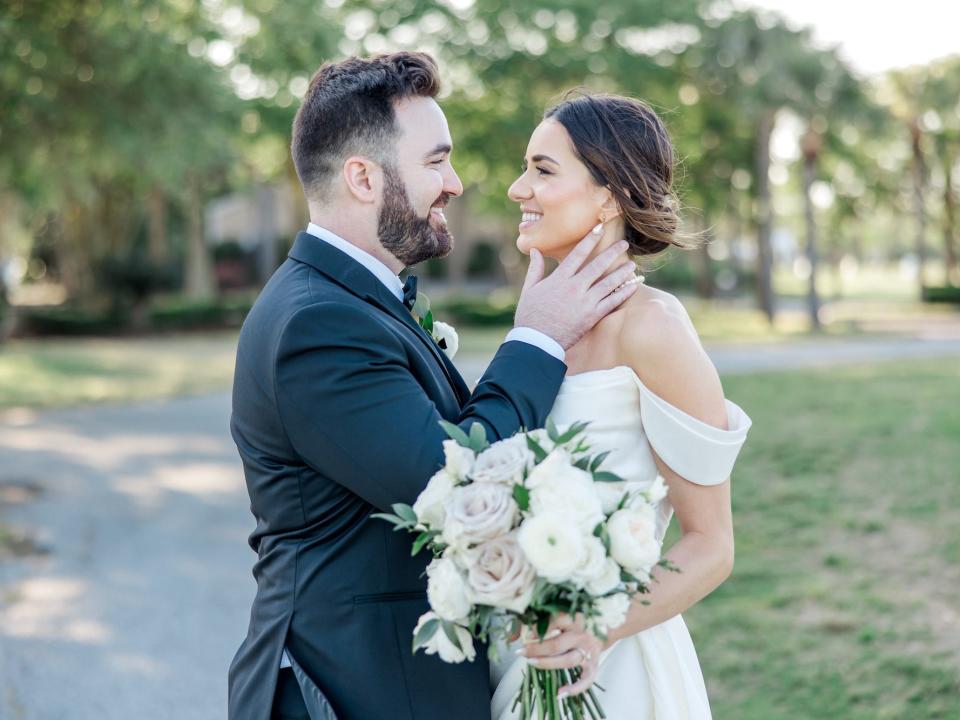 A groom touches his bride's face as they gaze into each other's eyes.