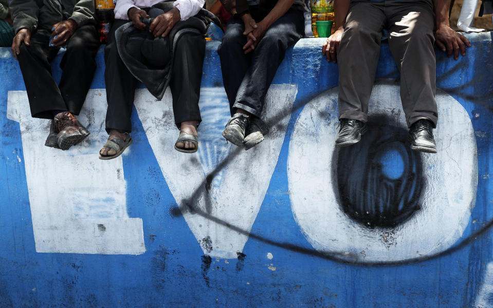 FILE - In this Nov. 17, 2019 file photo, supporters of former President Evo Morales sit over a mural emblazoned with his first name, in Sacaba, Bolivia. Morales, a 60-year-old former coca farmer and union leader, faces terrorism and other charges in Bolivia and is not an election candidate in the upcoming October elections. Some human rights advocates believe the charges amount to political persecution of Morales. (AP Photo/Juan Karita, File)