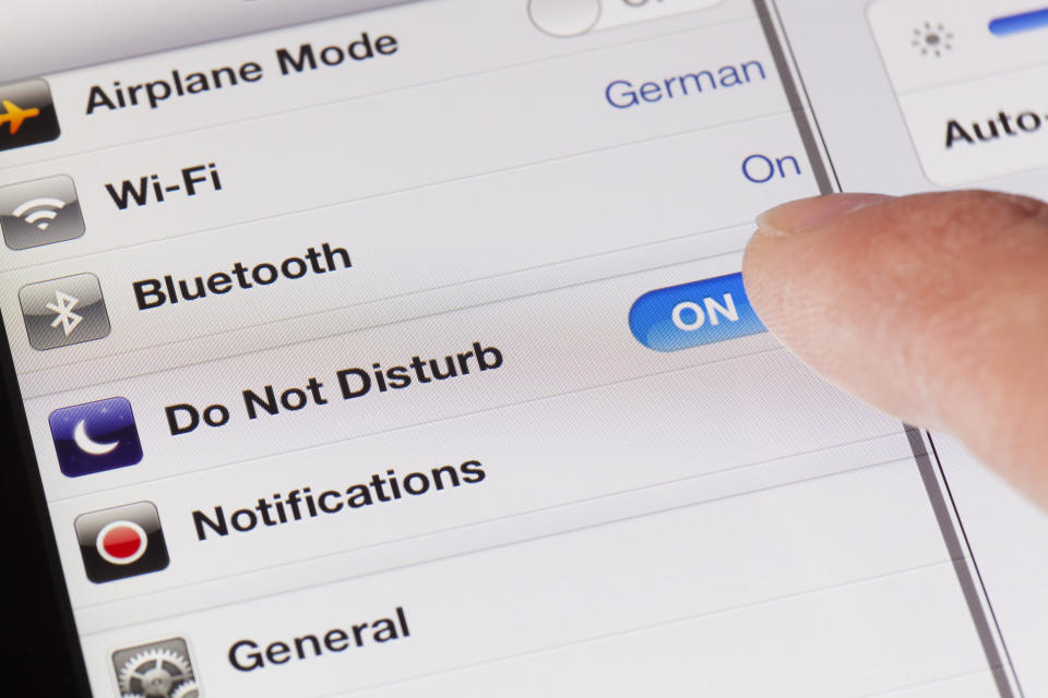 Close-up of a smartphone screen showing Airplane Mode on, Wi-Fi off, Bluetooth on, and Do Not Disturb on being activated by a finger