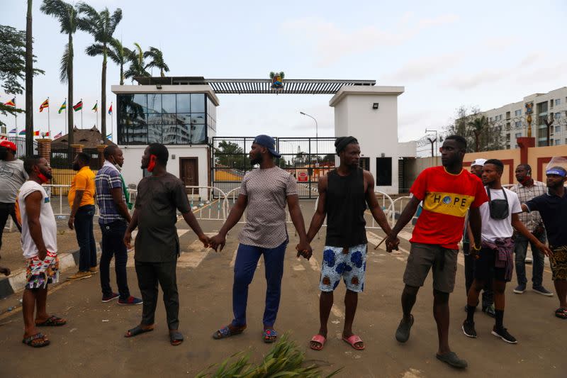 Demonstrators hold hands as they gather near the Lagos State House