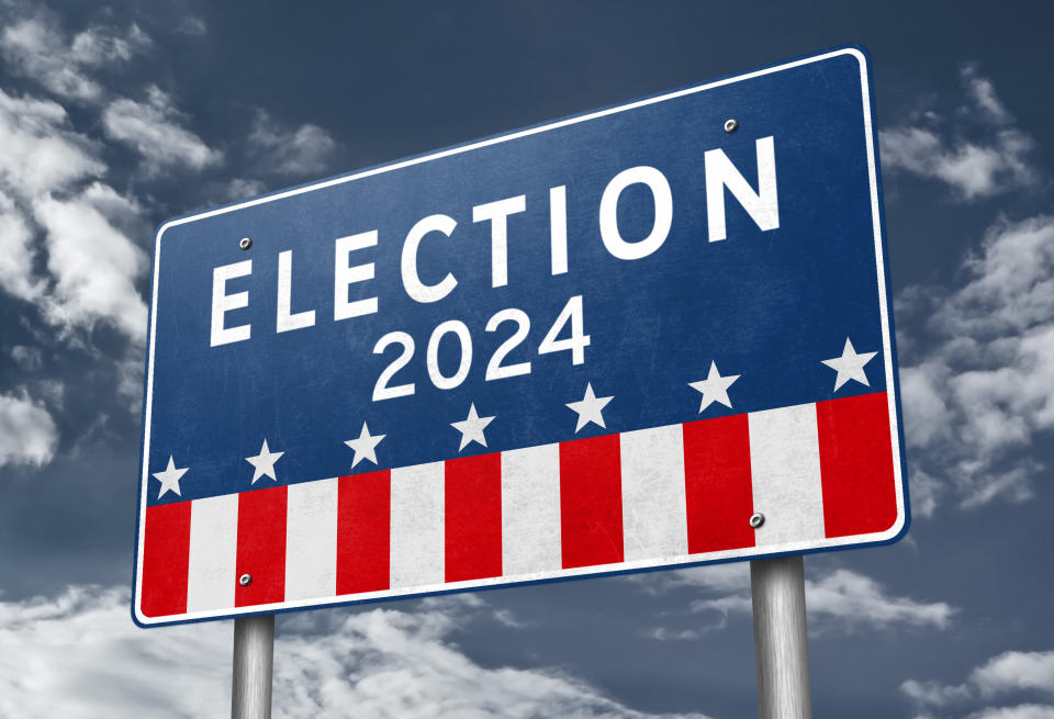 Sign reading "ELECTION 2024" with patriotic stars and stripes, against a cloudy sky