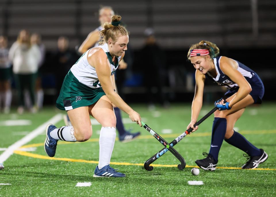 Dover's Audrey Carter, left, works the ball past Exeter's Dani Caron during Tuesday's Division I field hockey semifinal.