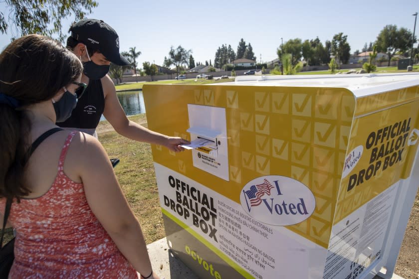 SANTA ANA, CA - OCTOBER 13: Caitlin Harjes, left, of Orange, and Angel Santiago, of Santa Ana, place their ballots inside an official Orange County Registrar of Voters ballot Drop Box for the 2020 Presidential General Election at Carl Thornton Park in Santa Ana on Tuesday, Oct. 13, 2020. (Allen J. Schaben / Los Angeles Times)