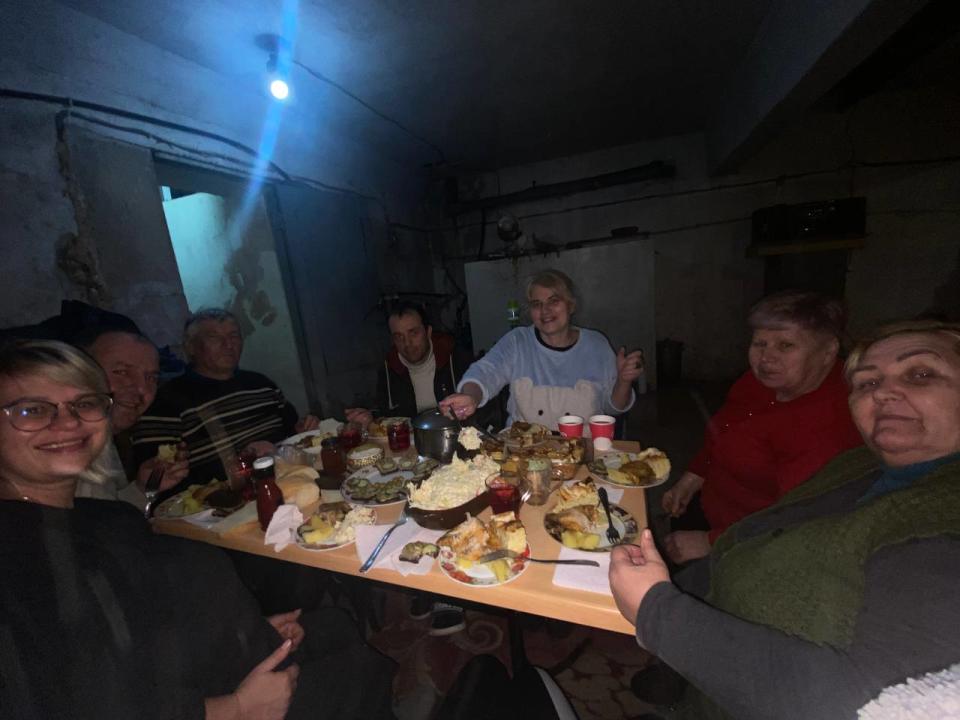A group of Ukrainians, including a heavily-pregnant Galina Diakonenko, sit around a table in the basement which served as a bomb shelter.