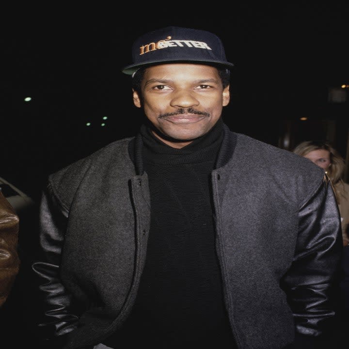 Denzel Washington, wearing a grey jacket over a black turtle neck sweater, with a 'Mo' Better Blues' baseball cap, in Los Angeles, California, 1990